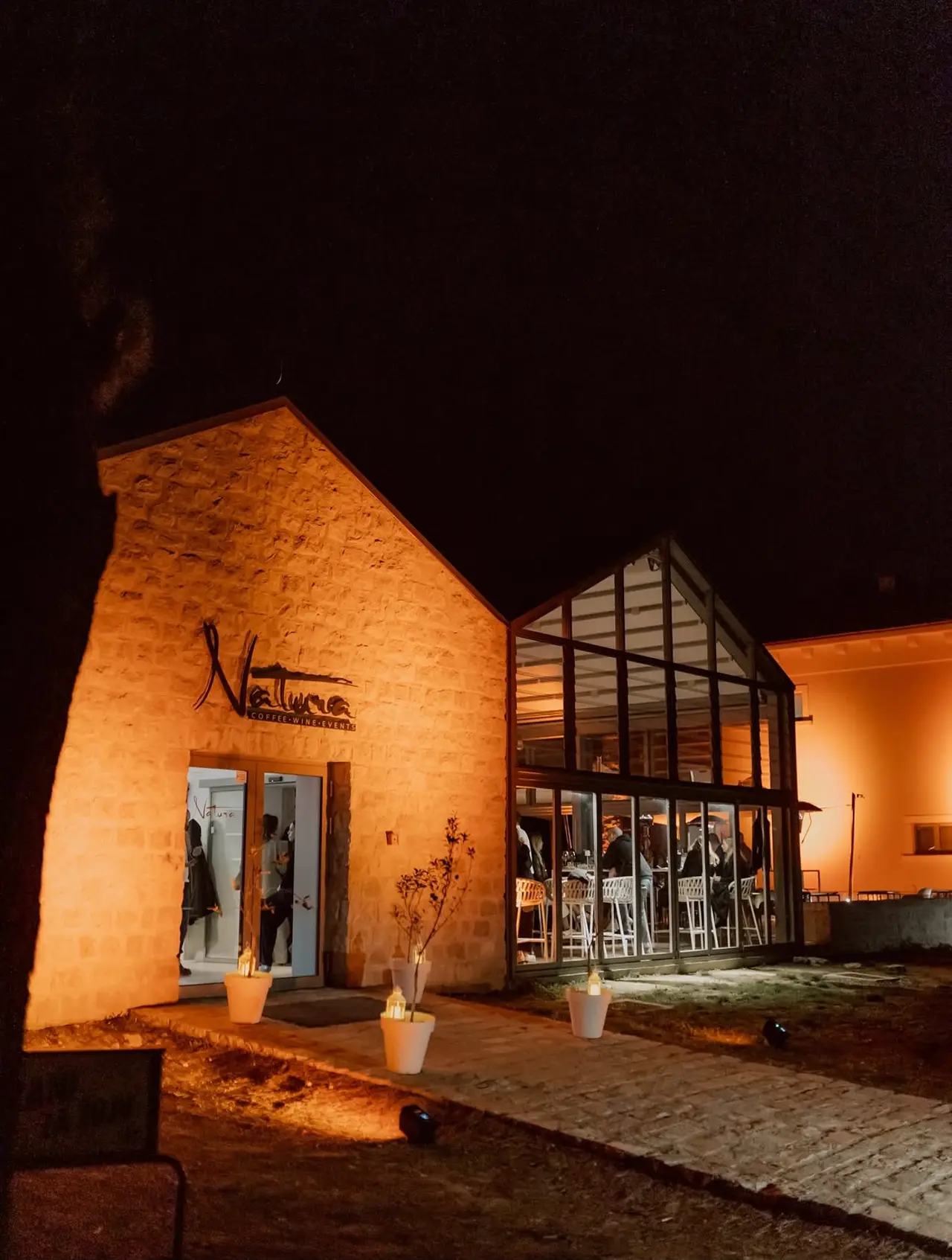 Vanjski noćni pogled na elegantni prostor Coffee Wine Bar Natura u Šibeniku, koji prikazuje profesionalno postavljenu ambijentalnu rasvjetu za elegantno vjenčanje ili DJ event.