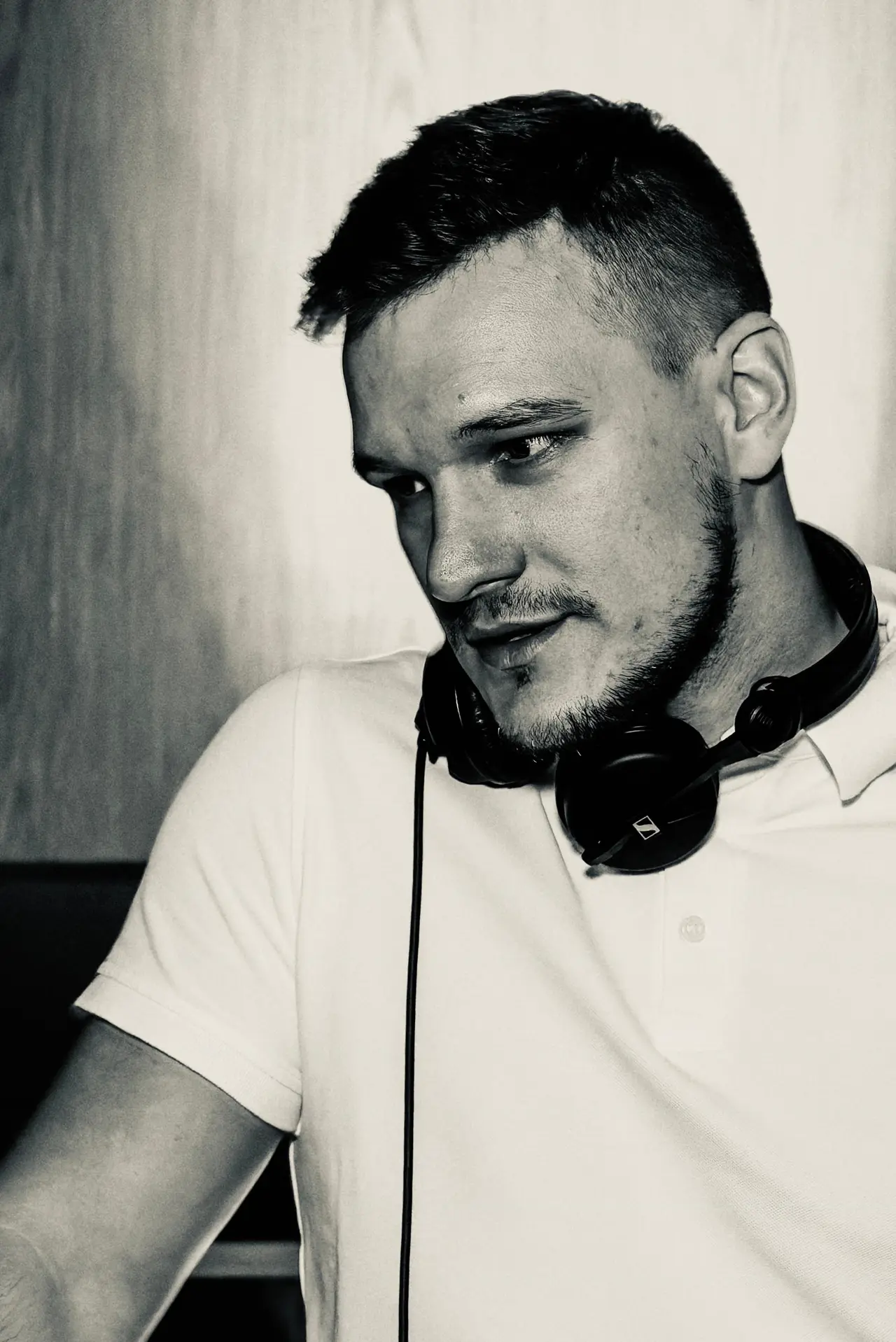 Profesionalni crno-bijeli portret osnivača i DJ-a, Petar Čelar, sa slušalicama, spreman za vođenje ekskluzivne gala večeri